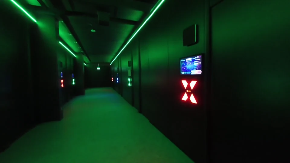 An installed corridor of Fabricats game rooms with wristband check-in screens beside the doors.